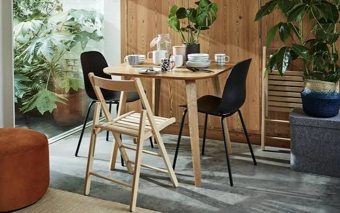 Round oak dining table with folding oak chairs and black shell chairs.